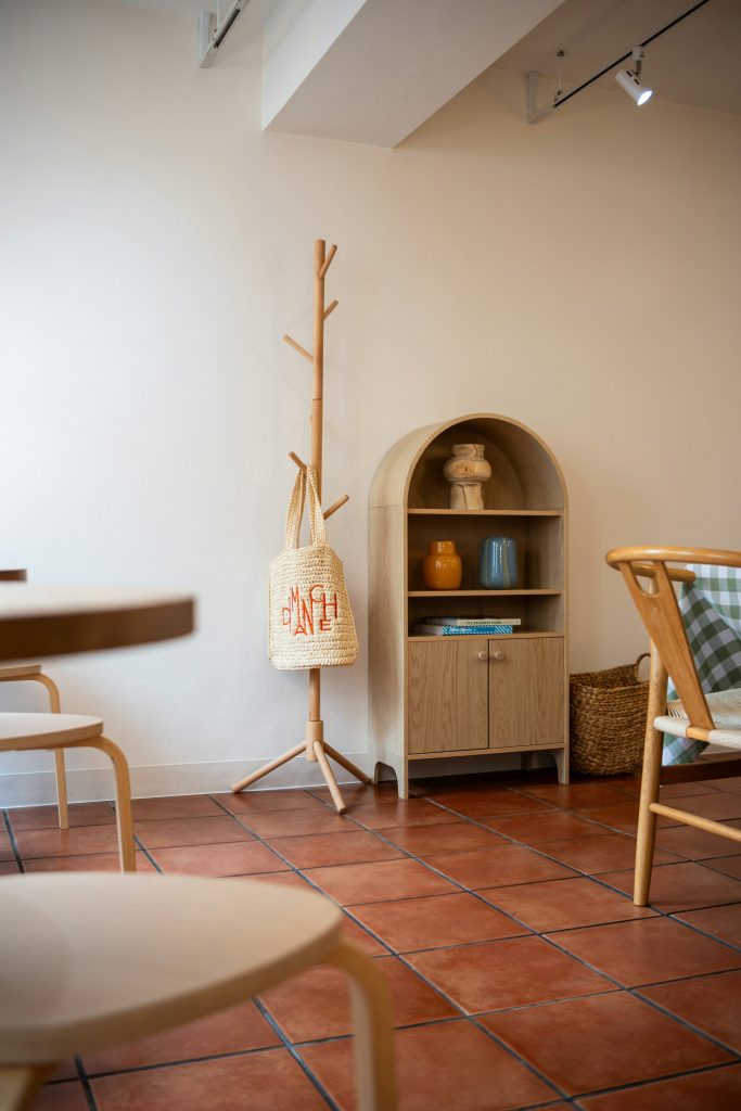 Wooden coat stand, woven bag and shelving in an interior.